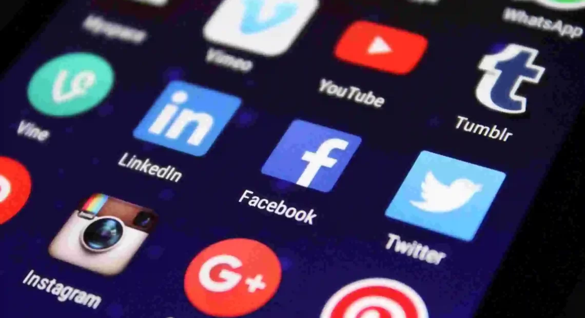Smartphone screen displaying popular social media app icons including Facebook, Twitter, YouTube, Instagram, LinkedIn, WhatsApp, and Tumblr, representing online platforms and digital communication.