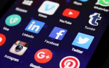 Smartphone screen displaying popular social media app icons including Facebook, Twitter, YouTube, Instagram, LinkedIn, WhatsApp, and Tumblr, representing online platforms and digital communication.