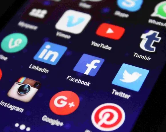 Smartphone screen displaying popular social media app icons including Facebook, Twitter, YouTube, Instagram, LinkedIn, WhatsApp, and Tumblr, representing online platforms and digital communication.