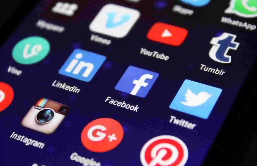 Smartphone screen displaying popular social media app icons including Facebook, Twitter, YouTube, Instagram, LinkedIn, WhatsApp, and Tumblr, representing online platforms and digital communication.